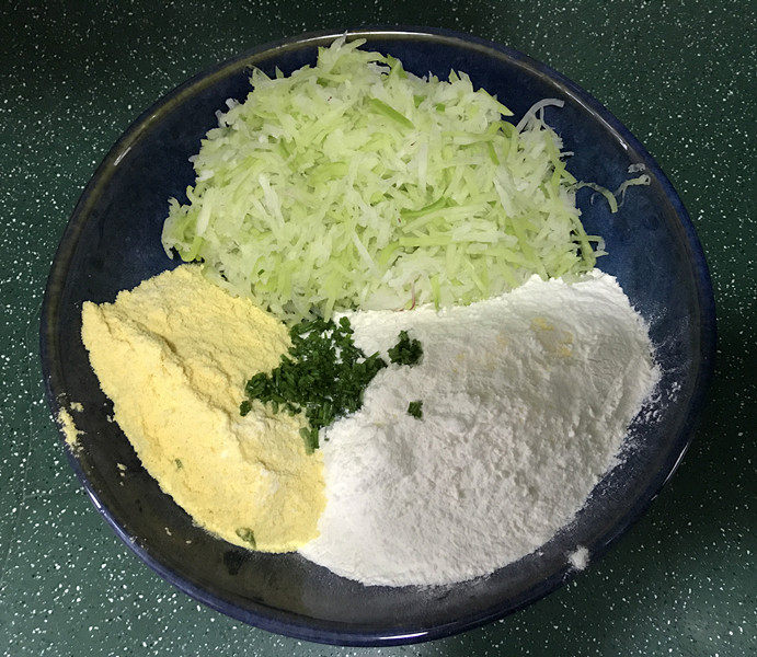 黄金玉米饼,碗中放入萝卜丝、玉米面和普通面粉,再加入盐和葱花