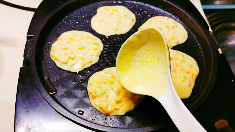 鲜虾玉米饼,煎烤机刷油预热,用勺子倒入面糊。
