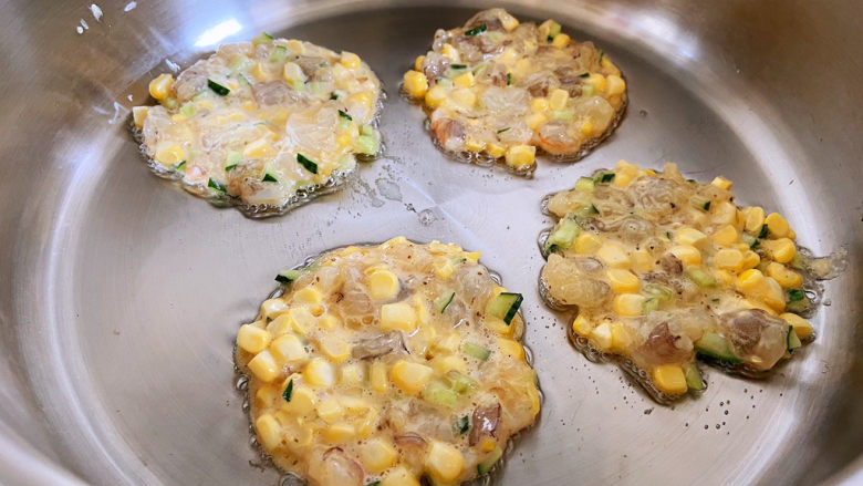 鲜虾玉米饼,锅中油烧热以后改小火,用勺子舀到锅中,尽量每一勺的量都差不多,这样可以使虾饼大小都差不多。