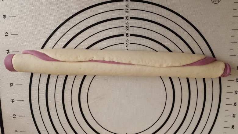 紫薯小馒头,在紫薯面片上刷层水,开始从底部卷起,尽量卷紧密一些。然后搓一下,使之粗细均匀