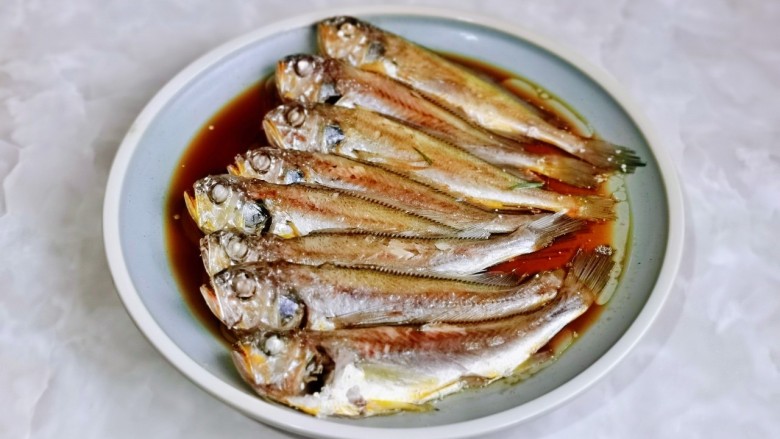 香辣小黄鱼,取出蒸好的鱼,把姜丝葱段夹掉,盘子里的汤汁倒掉,淋上一勺生抽。