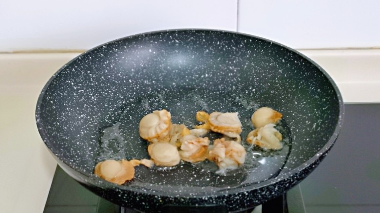 扇贝炒鸡蛋,另起油锅,加入腌制好的贝肉翻炒2分钟,盛出备用。