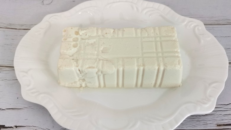 小葱拌豆腐,豆腐撕开封塑膜,倒扣在盘中剪掉四个角,轻松脱出