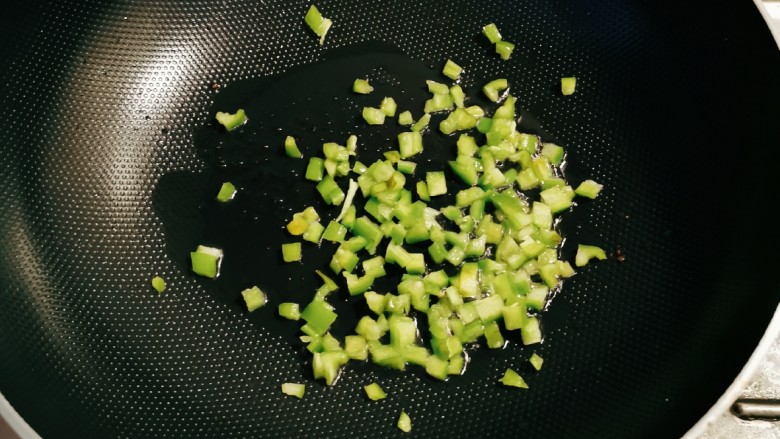 肉沫蒸豆腐,起油锅放入1汤匙食用油,油热后放入青椒丁翻炒断生,出锅备用。