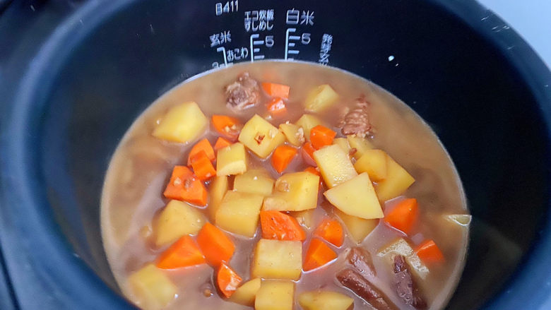 土豆排骨焖饭,先把排骨中的水倒入到米中,比平时做大米饭的水量要少一点,因为米已经泡过半小时了,然后加入排骨等材料。