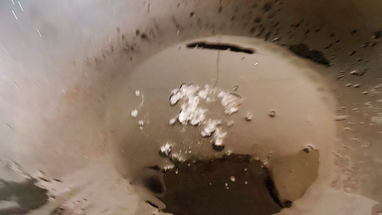 土豆排骨焖饭,先爆锅,油热了放入冰糖,一边加热一边将冰糖拍碎。