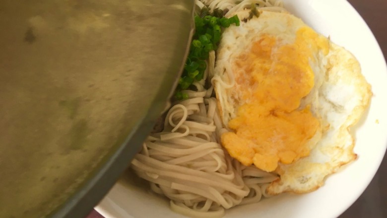 雪菜肉丝面,先夹出面条,把煎好的鸡蛋放在上面,撒上葱花,然后再把汤倒进去