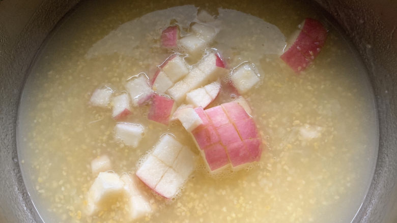 苹果小米粥,将苹果加入小米粥中。