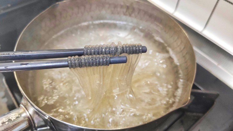 豆芽炒粉条,锅中加入适量清水,加入红薯粉,煮几分钟,红薯粉熟了就马上夹出来,不要煮的时间太长,以免红薯粉变得太软,容易断,影响整体口感。