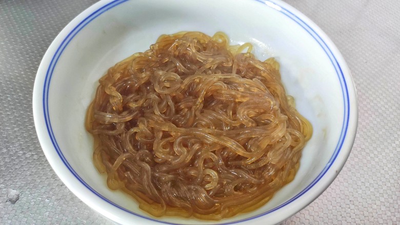 豆芽炒粉条,把红薯夹出来,直接放入碗中,加入一勺生抽和一勺食用油,搅拌一下,以免粉条互相粘连,备用。