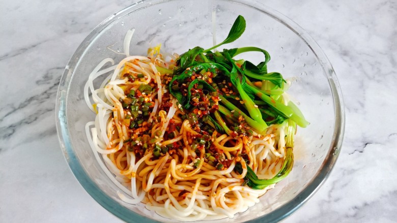 猪油拌面,面条、豆芽、青菜捞到大一点的容器里面,淋上料汁,用筷子搅拌翻转,让每根面条能够与酱汁互相融合在一起。