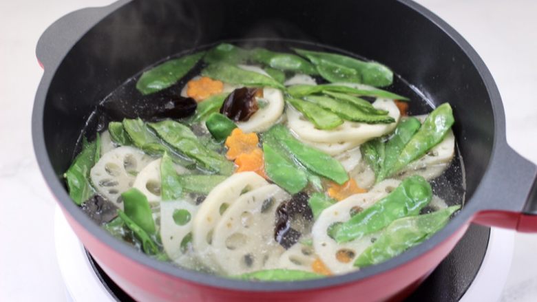 清爽营养的小炒鲜,锅中倒入适量的清水烧开后,加入少许盐和食用油,放入藕片和眉豆,胡萝卜和木耳。