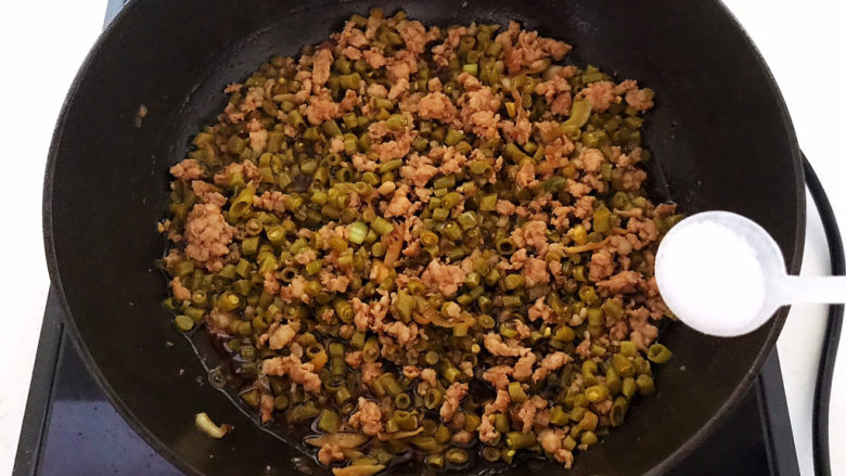 酸豆角炒肉末,加入精盐,翻炒均匀
