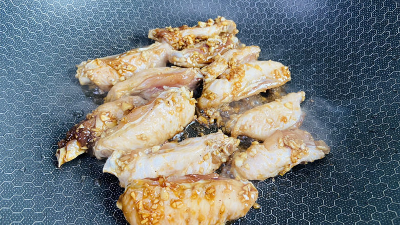 蒜香鸡翅,锅中加入少许食用油加热至五成热,放入鸡翅