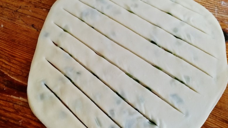 饺子皮葱油饼,擀成薄饼,中间划几刀。