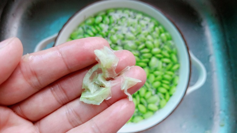 毛豆炒肉丝,用手轻轻揉揉毛豆,把毛豆外面一层外衣搓下来。