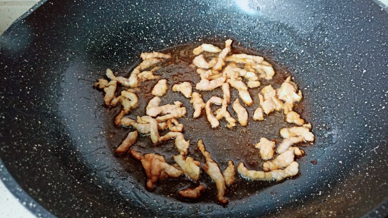 毛豆炒肉丝,锅里倒入适量的食用油,凉油下蒜泥炒香。下入肉丝煸炒至变色。