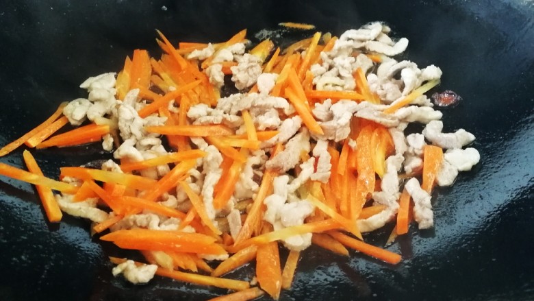 毛豆炒肉丝,放入胡萝卜丝和肉丝一起文火炒匀,把胡萝卜炒软。