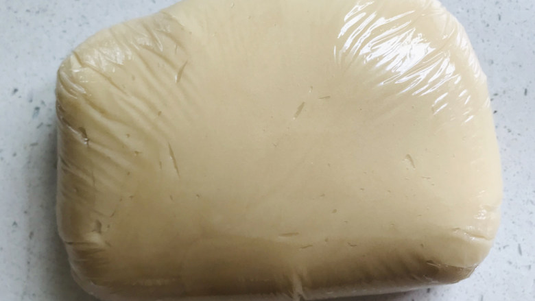 莲蓉蛋黄月饼,拌匀之后的月饼皮,用保鲜膜包起来,然后室温静置3小时左右。
