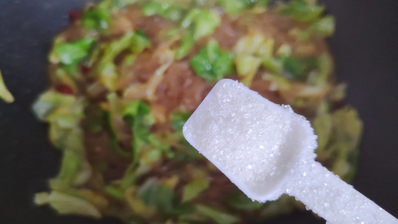 包菜炒粉丝,待锅内汤汁差不多收紧,加一小勺细砂糖,翻炒均匀即可