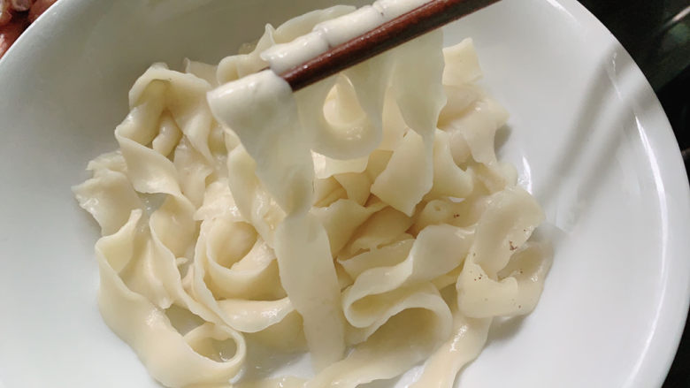 新疆大盘鸡,因为宽带面有一定厚度,沸腾后,转小火再煮1~2分钟,让宽带面熟到透彻,并铺在盘底。