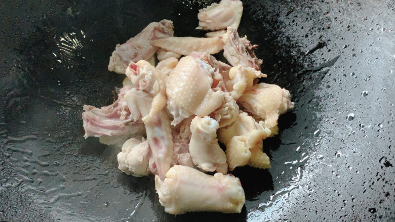 新疆大盘鸡,加入焯过水的三黄鸡块,转中火煸炒,让鸡皮在油锅中炒出香味。