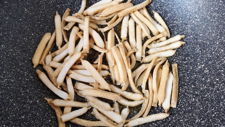 包菜炒粉丝,炒锅内倒适量的食用油烧热,下入豆腐干炸至金黄色,盛出备用。
