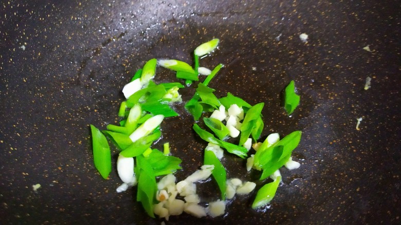 丝瓜炒蛋,锅中再加少许油,加入葱花和蒜末炒出香味。