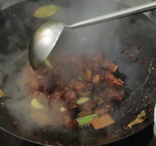 红烧羊排,色泽炒至均匀以后从锅中淋入料酒5克,因为料酒在加热的过程中挥发能减少羊排的腥味