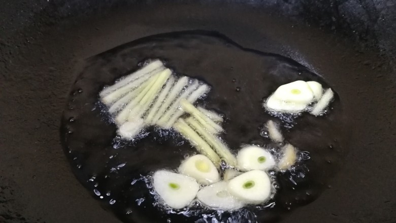 香菇肉片,热锅凉油,油微热放入姜丝和蒜片,文火炒香。