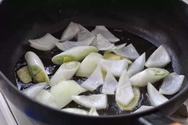 红烧牛腩,另起锅倒适量食用油烧至五成热,放入葱段、姜片和洋葱,小火炒出香味。