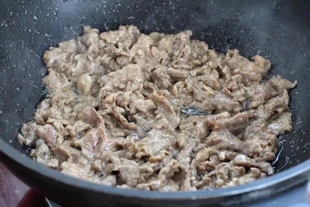 小炒牛肉,锅中倒适量食用油烧至五成热,下入腌制好的牛肉炒至变色盛出。