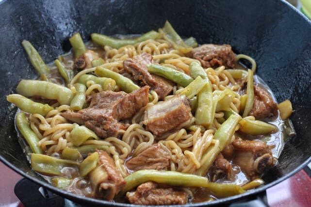 排骨豆角焖面,待面条焖熟后用筷子与锅中其他食材混合拌匀,使之裹上汤汁即可。