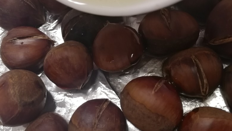 糖炒板栗,板栗放在铺锡纸的烤盘上,淋上油糖汁。