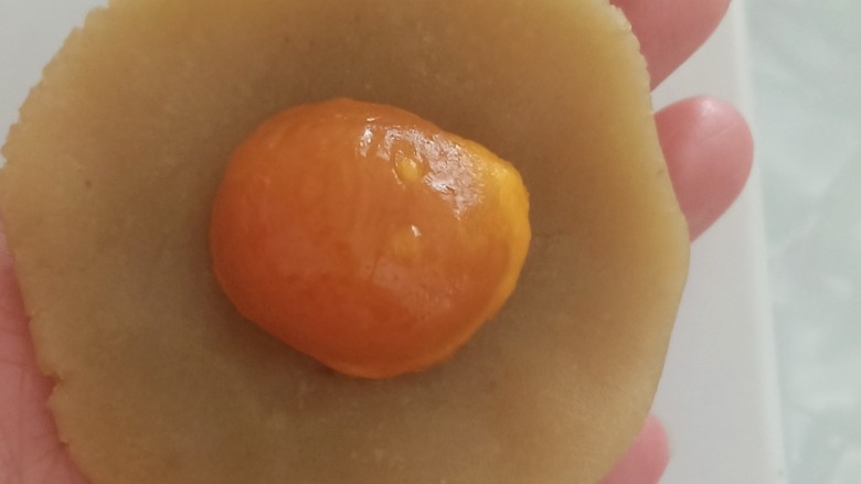 蛋黄莲蓉月饼,取一个白莲蓉,按扁,包入一颗熟蛋黄