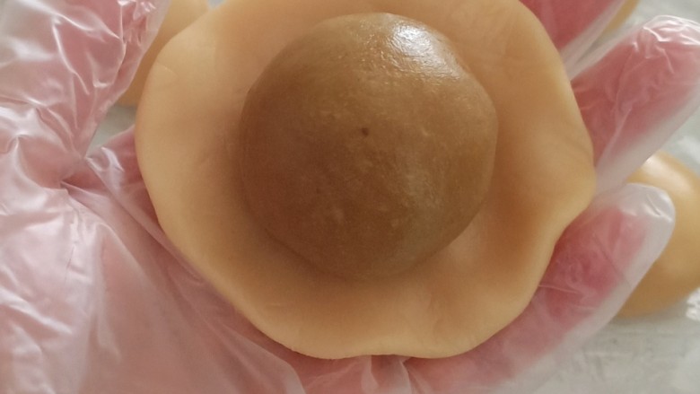 蛋黄莲蓉月饼,把月饼皮按扁,包入蛋黄莲蓉,收口朝下