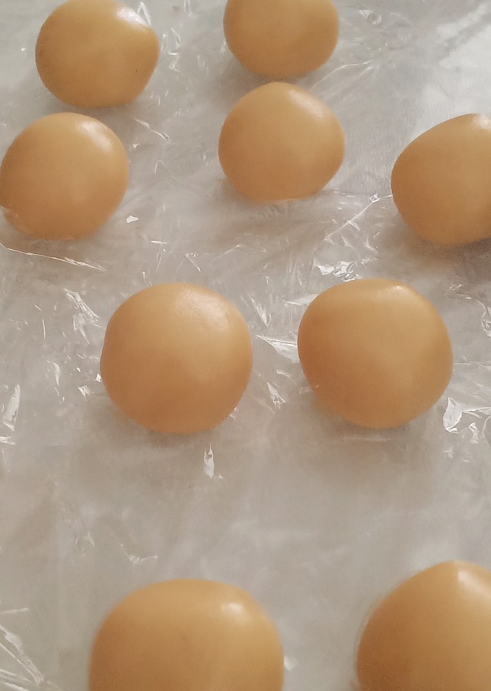 蛋黄莲蓉月饼,面团松弛一个小时后,放在面板上再揉一揉。搓成长条,分成20克一个个的小剂子,搓圆,月饼皮就完成了