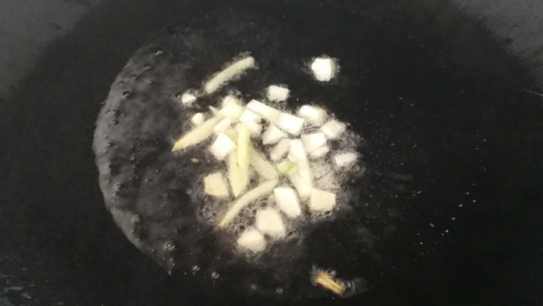茭白炒肉丝,热锅凉油,有微热放入姜丝和蒜末,文火炒香。