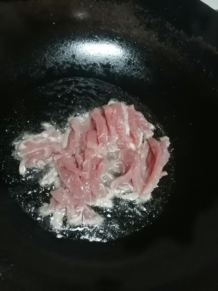 茭白炒肉丝,开火加热锅倒入油,倒入肉丝翻炒。