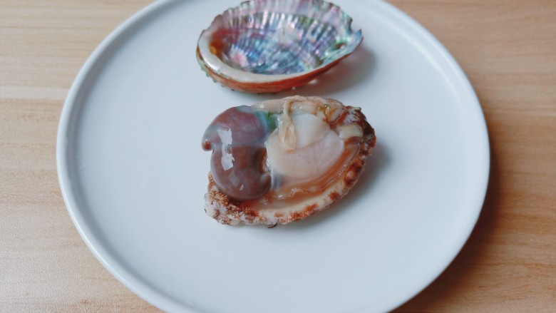 清蒸鲍鱼,用勺子贴着小鲍鱼的壳。轻轻一挖就出来了,切掉小鲍鱼的内脏部分,壳里残余的肉也刮干净。