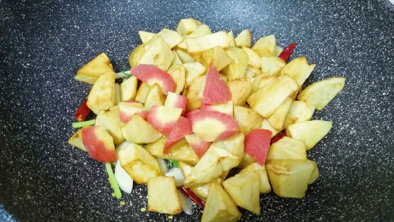 红烧土豆,下入红萝卜和煎好的土豆翻炒均匀。