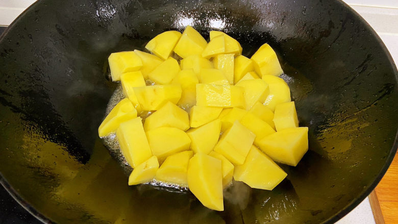 红烧土豆,冰糖溶化后应该先把大蒜放进锅中煸炒上色出香味,再把姜和葱末倒进去翻炒均匀,然后再加入土豆翻炒,我炒的时候顺手先放了土豆。