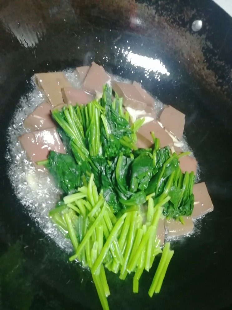 鸭血炒菠菜,加菠菜翻炒。