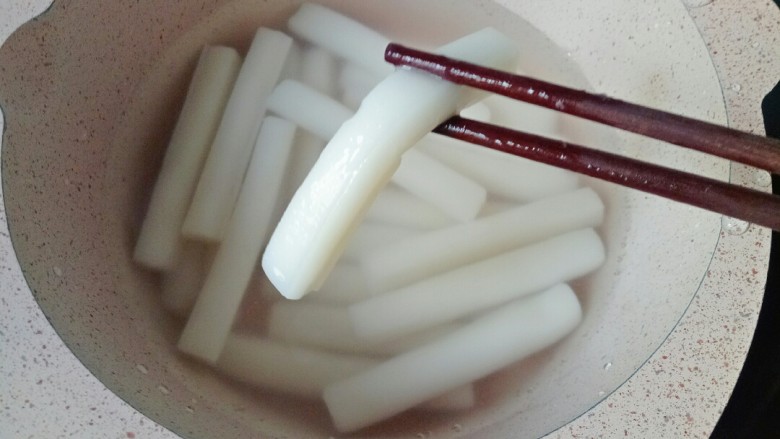 爆炒基围虾,锅中加入适量清水煮开,放入年糕煮两分钟捞出过凉水