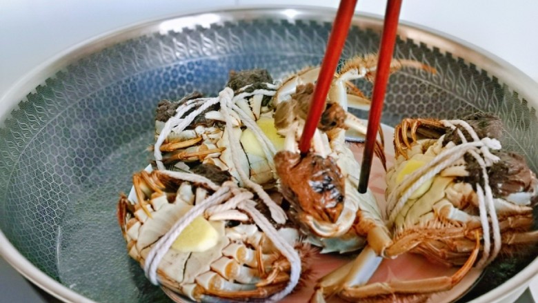 清蒸螃蟹,上锅隔水蒸,大火烧开后,转中小火蒸15分钟,再焖2分钟。(一共四只蟹,被孩子给绳子剪开玩了一会儿!结果备受折磨呀!把锅盖都顶起来了……无奈用筷子按住它,直到没有反抗能力放开!!)