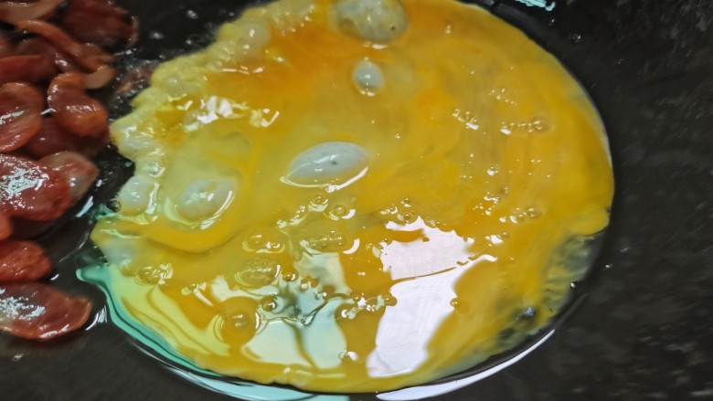 腊肠炒鸡蛋,煸香后的腊肠捞放一边,鸡蛋下锅煎至