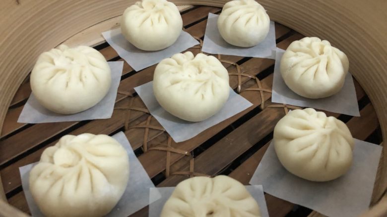 梅干菜肉包,蒸笼里放入纸垫,把包好的包子放进去盖盖,等它第二发酵,怎么确定它有没有发好,手指按一下有蓬松的感觉就可以了,(明显是比刚包的时候大半倍)