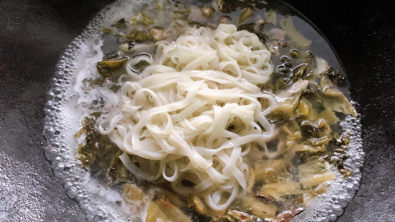 酸菜肉丝面,夹起后,加入一侧沸腾好的酸菜肉丝汤底中