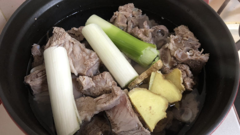 红烧羊肉,把洗干净的羊肉加入铸铁锅,加上葱姜和料酒,加入水和羊肉齐平