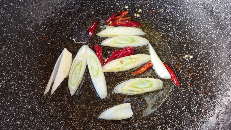西芹炒牛肉,锅里留余油继续烧热,下入大葱和干红辣椒炒香。